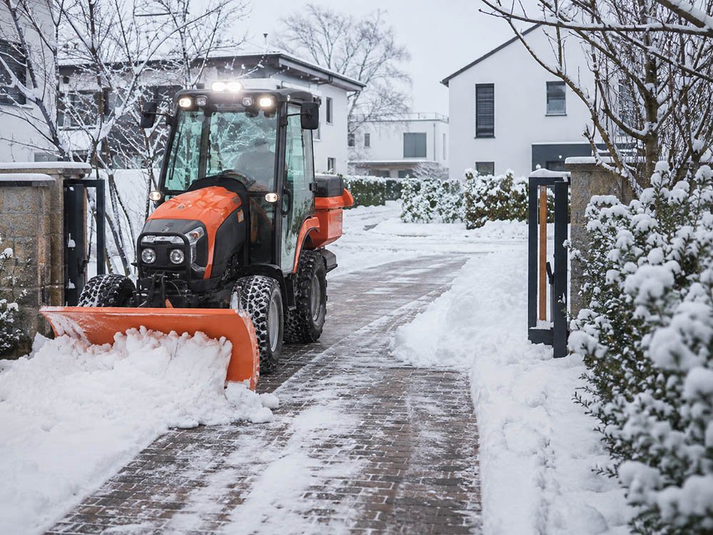 Winterdienst mit Traktor und Schneeschild beim R&auml;umen einer verschneiten Zufahrt in Vlotho